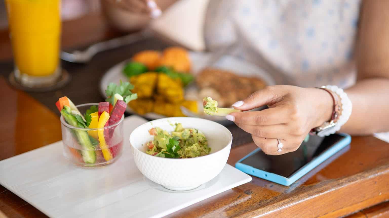 A person eating a salad and using a mobile app to record daily calories