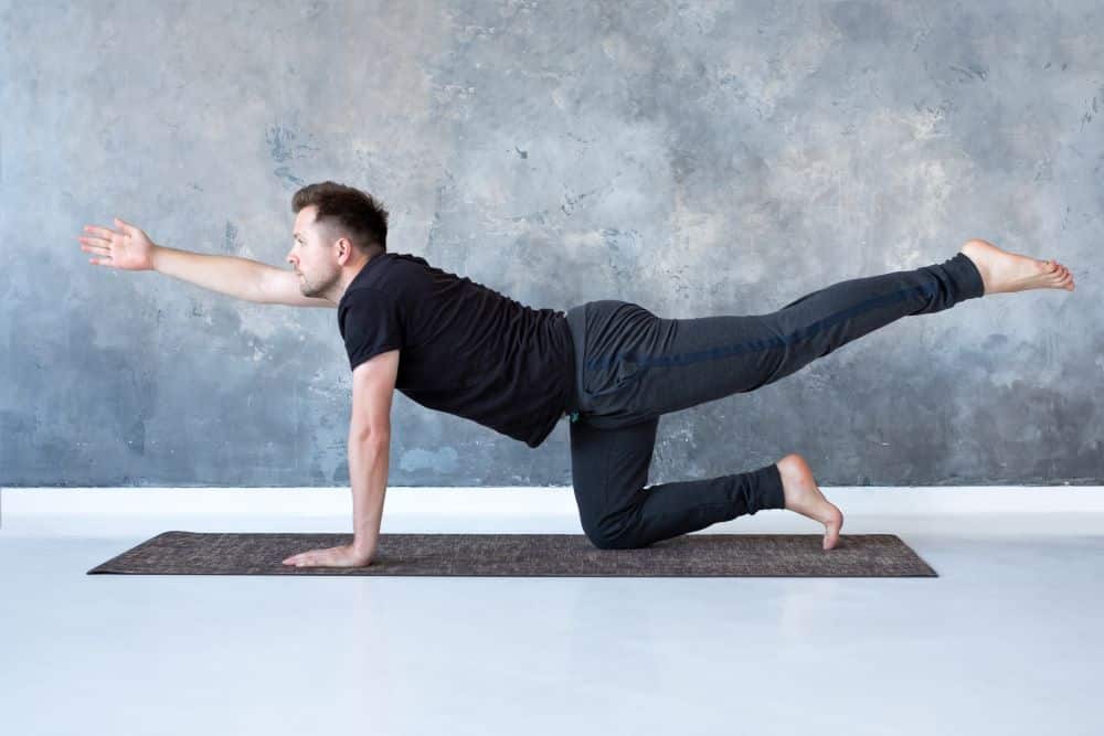 a young man does a bird dog mobility training exercise