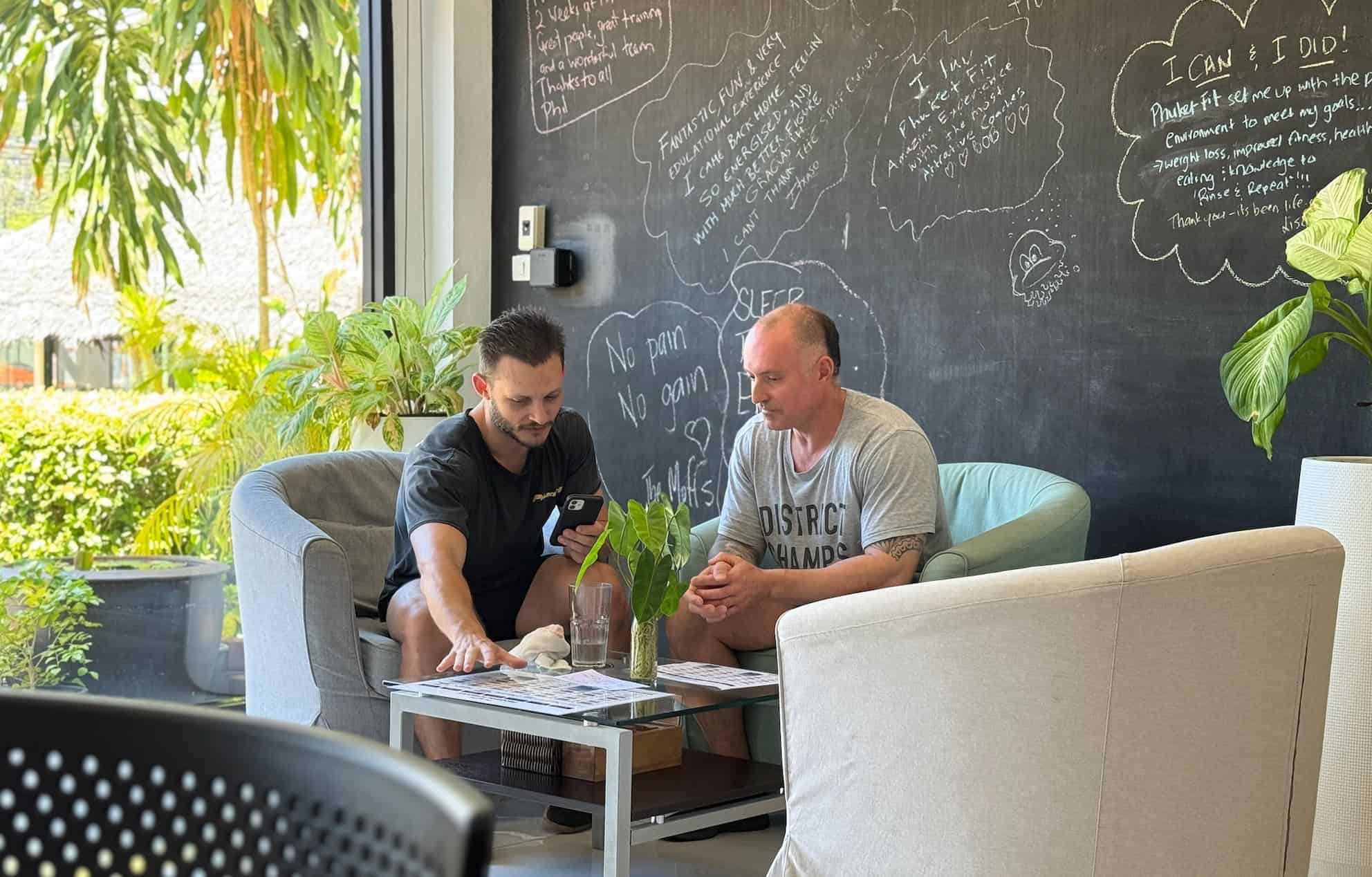 Screenshot Fitness instructor shows his client a personalized fitness program on a smartphone